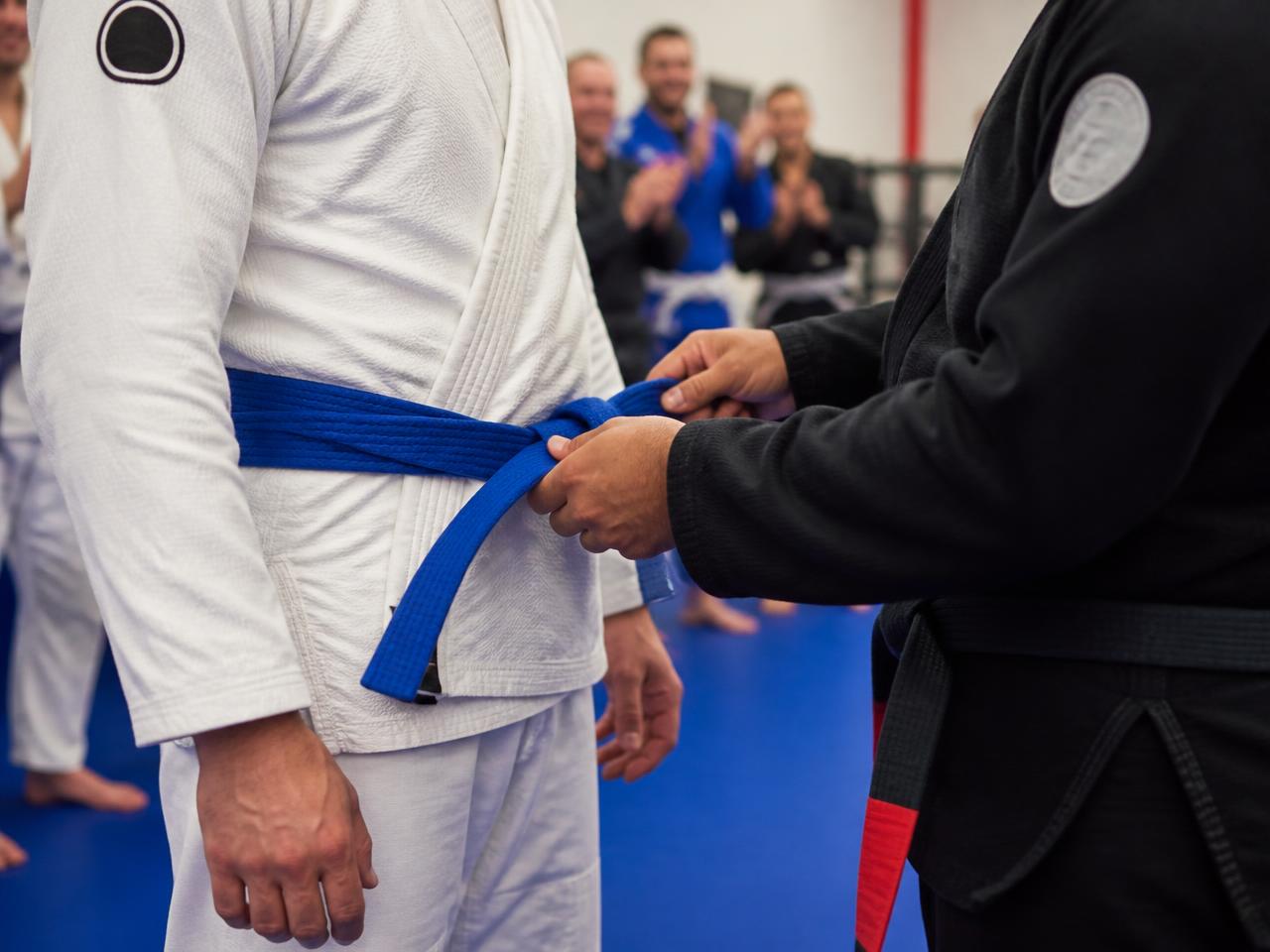 Adult student receiving his blue belt from the head instructor