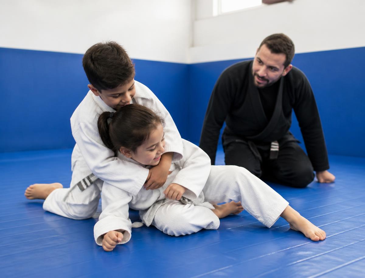 Kids drilling a supervised escape on the mat